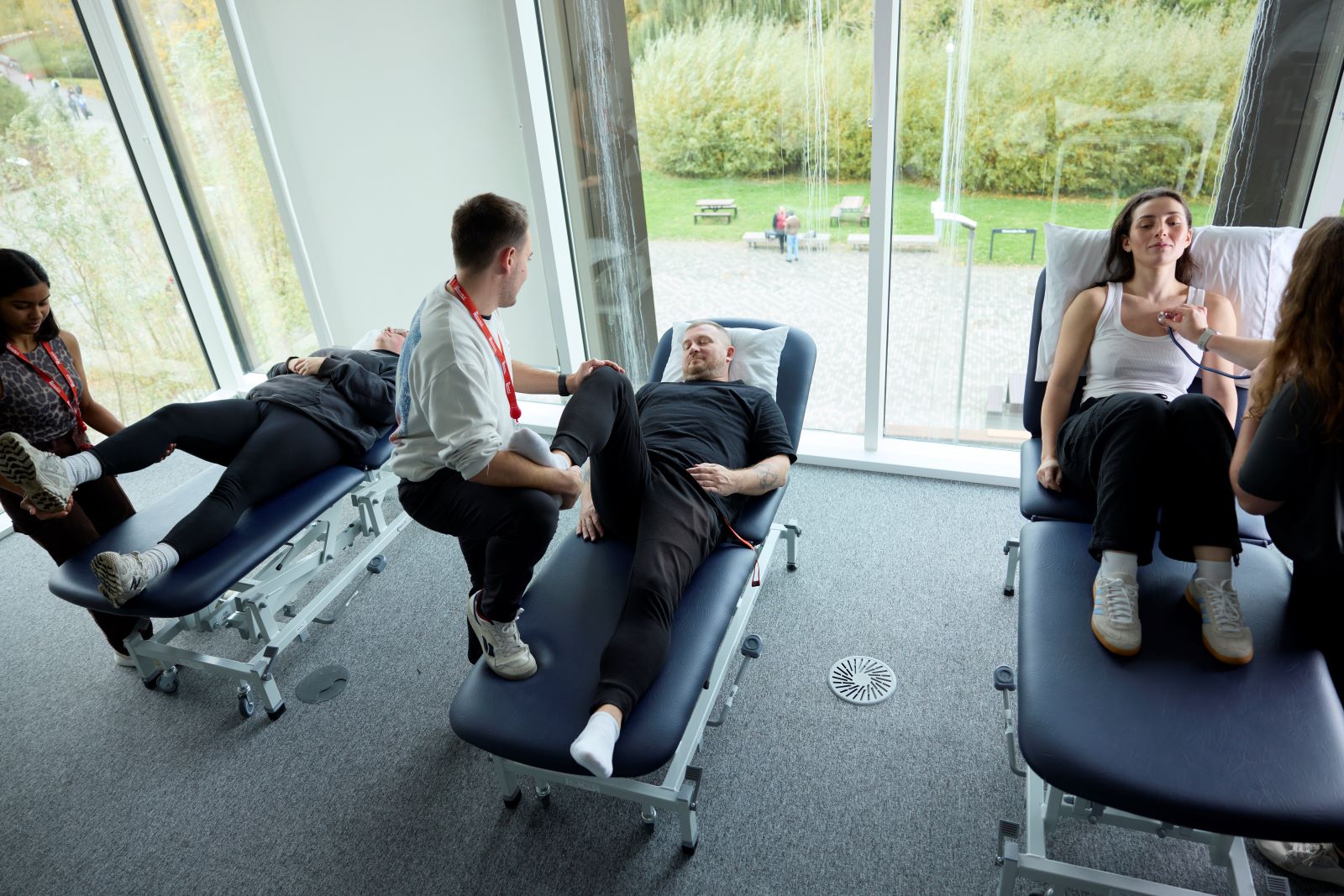 Three students practice their skills on three others, who are lying on consulting beds in the Phyiotherapy lab.