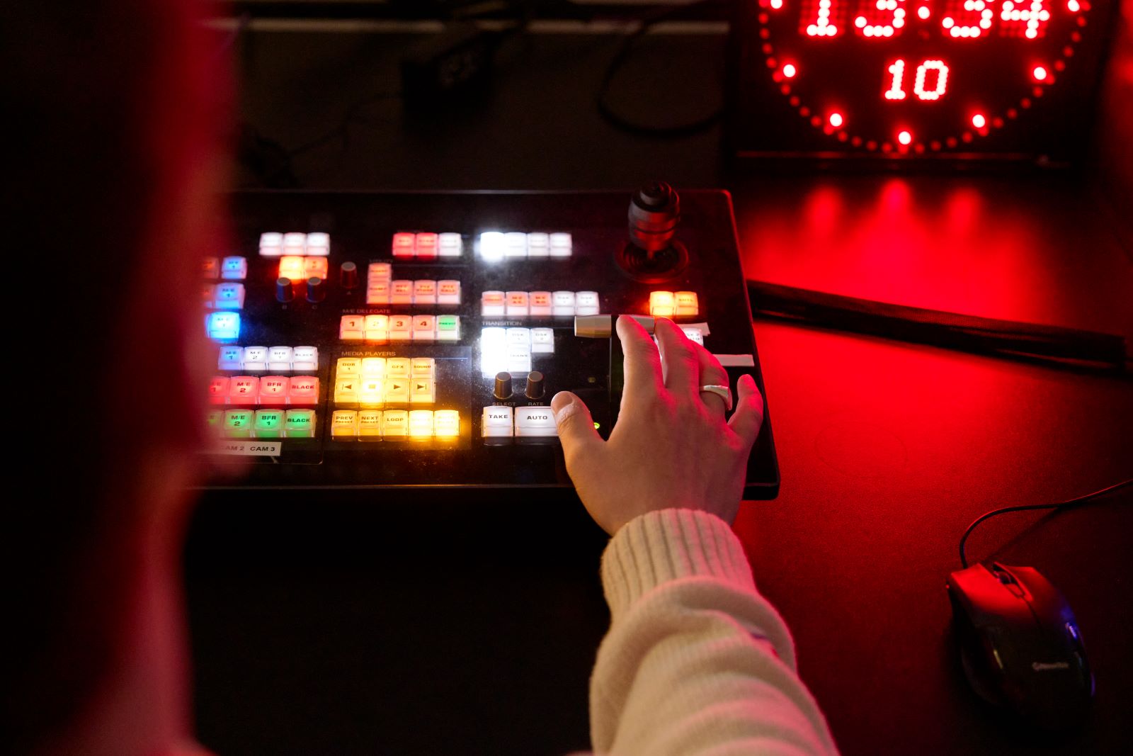 Student using a media desk in a dimly-lit studio. The desk features glowing, multicoloured buttons.