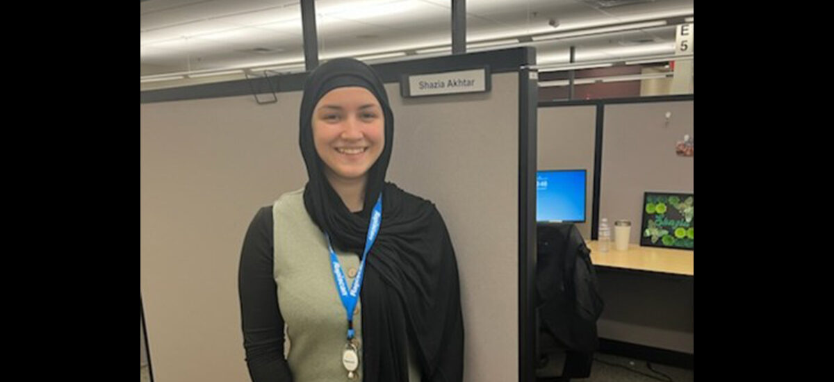 Shazia Akhtar, Accounting and Finance student standing in front of their own office space with their name on the entrance.
