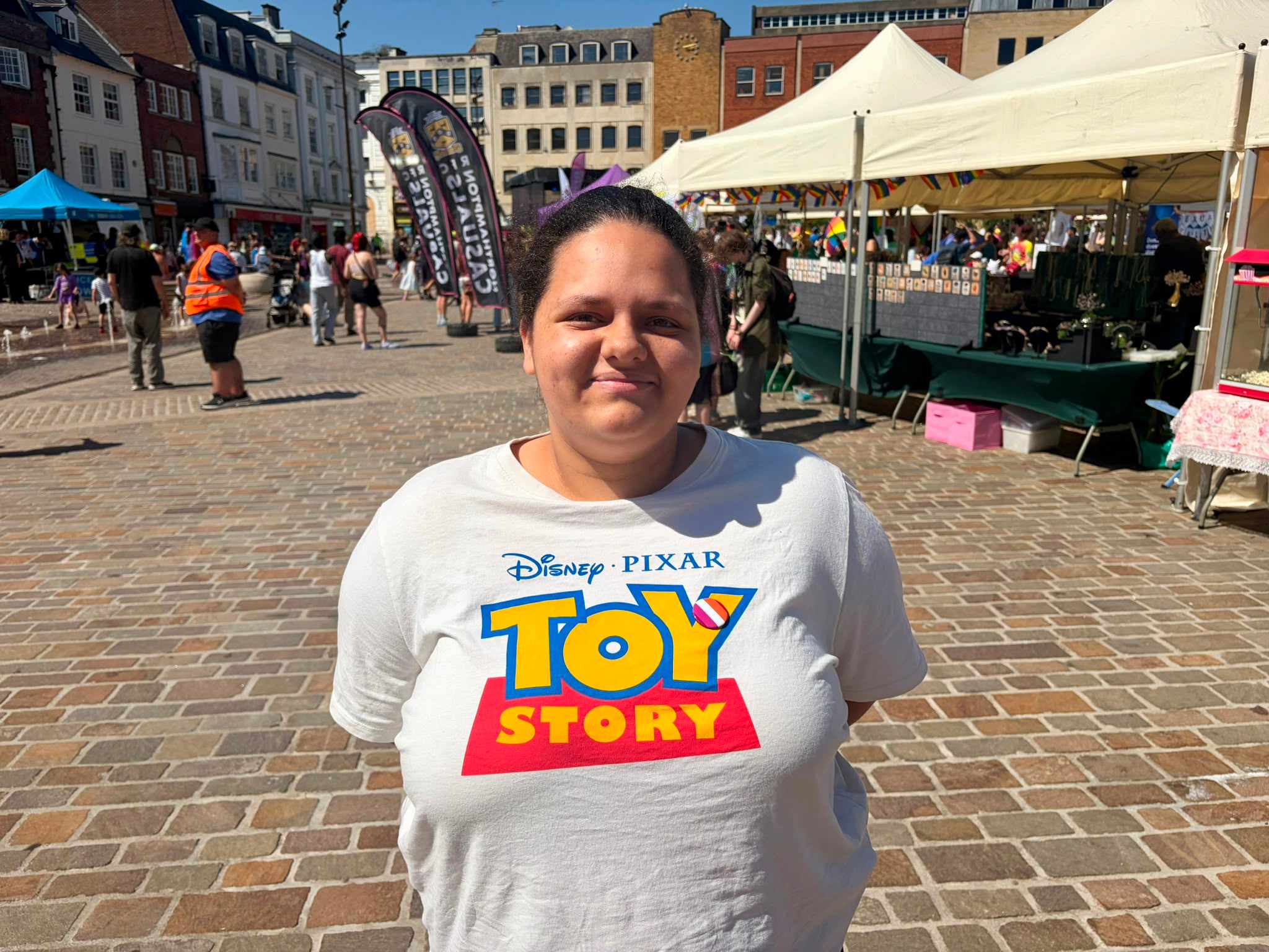 Ava smiles at the camera in the town market while wearing a toy story shirt.