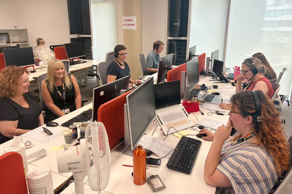 People sat at desks, looking at screens and answering calls.