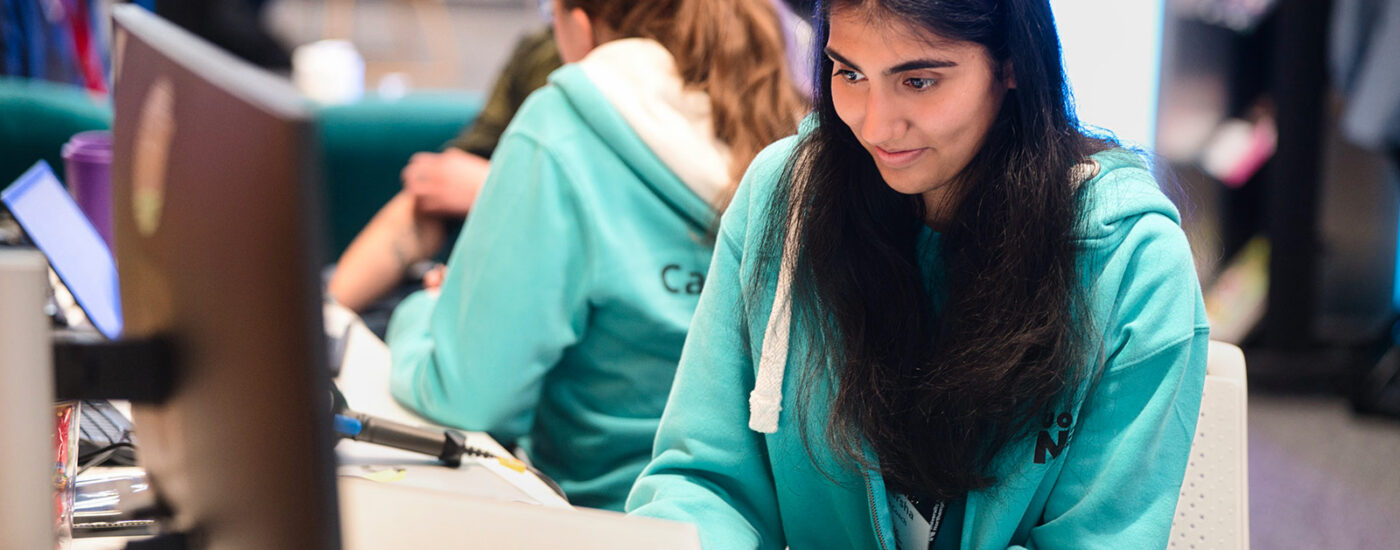 Uttkarsha Kapoor, sitting at a desk working on a laptop. She is wearing a Careers Team hoodie.
