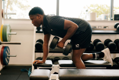 A student doing a bent over row with a dumbbell