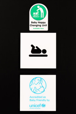 Close up of the signs on door at University of Northampton. Baby Nappy Changing Unit available here and Accredited as Baby Friendly by UNICEF United Kingdom
