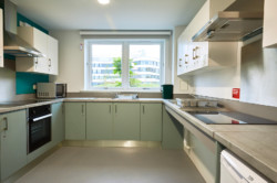 Kitchen area of Student Village, showing an oven, microwave, hob, kitchen sink, and a window showing the campus.