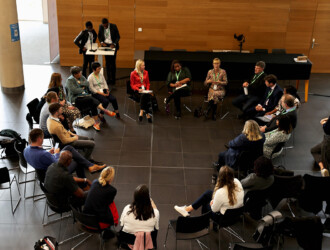 High angle view of approximately 20 delegates in a breakout session, sitting on chairs in a circle.
