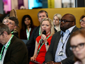 10 delegates in the crowd of a panel talk at the UON Sustainability Summit 2023. The person in the middle is holding a microphone, asking a question.