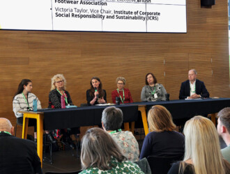 6 speakers at the UON Sustainability Summit 2023 at a panel table. The third person from the left is holding a microphone and talking to a crow where the backs of six people can be seen.