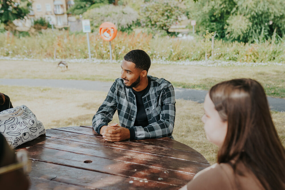 Students sitting at a bench under shade on campus