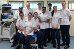 University of Northampton Podiatry students are pictured in uniform sitting on and around a treatment chair at the University’s Podiatry Clinic.