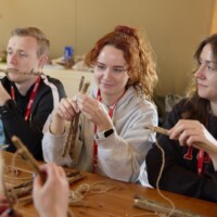 A photo of a student of Forest School undertaking a craft activity with sticks and thread.
