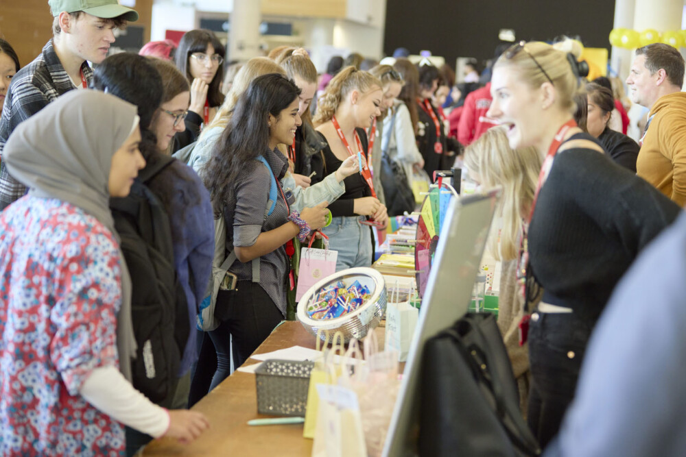 People gather around tables with items on display during the Student Union Societies Fair.