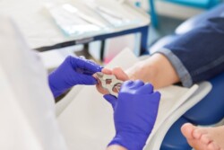 A person wearing purple gloves clipping a patient's toenails during a podiatry session.