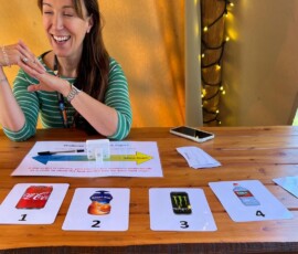 A person sat at a wooden table with four cards on the side ranking sugar in well known drinks from worst to best.