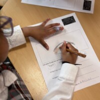 A birds eye view of a student drawing a hedgehog on a piece of paper