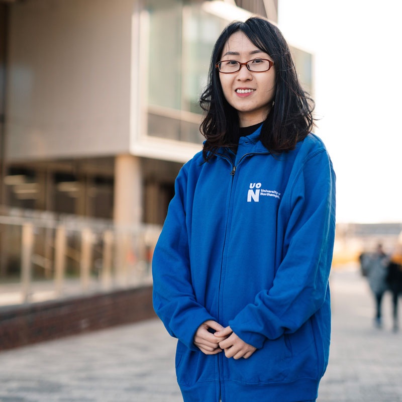 Photo of student ambassador, standing outside Learning Hub at an Open Day.
