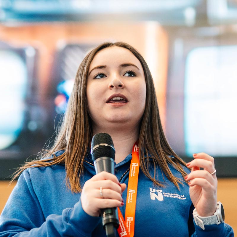 Student ambassador Jenna, delivering the Welcome talk at one of the University of Northampton Open Days and holding a microphone.