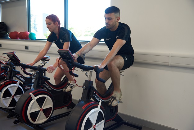 Two students riding wattbikes in an exercise studio